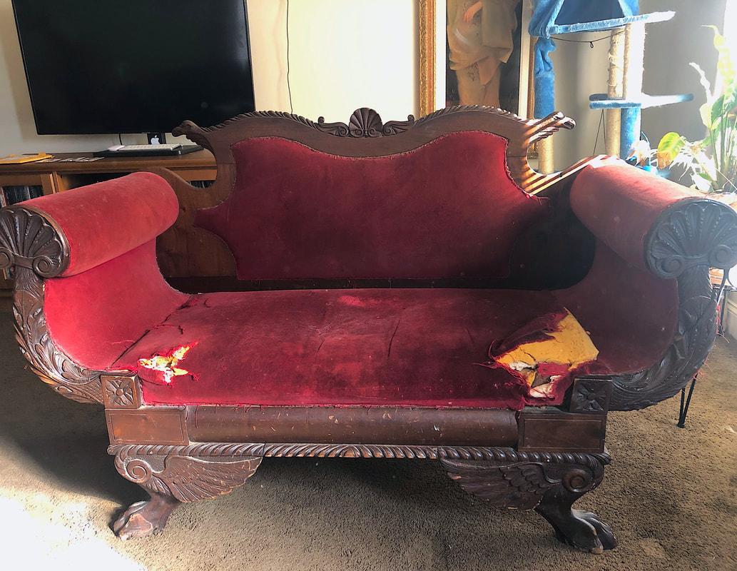 Antique settee with red fabric in need of restoration.