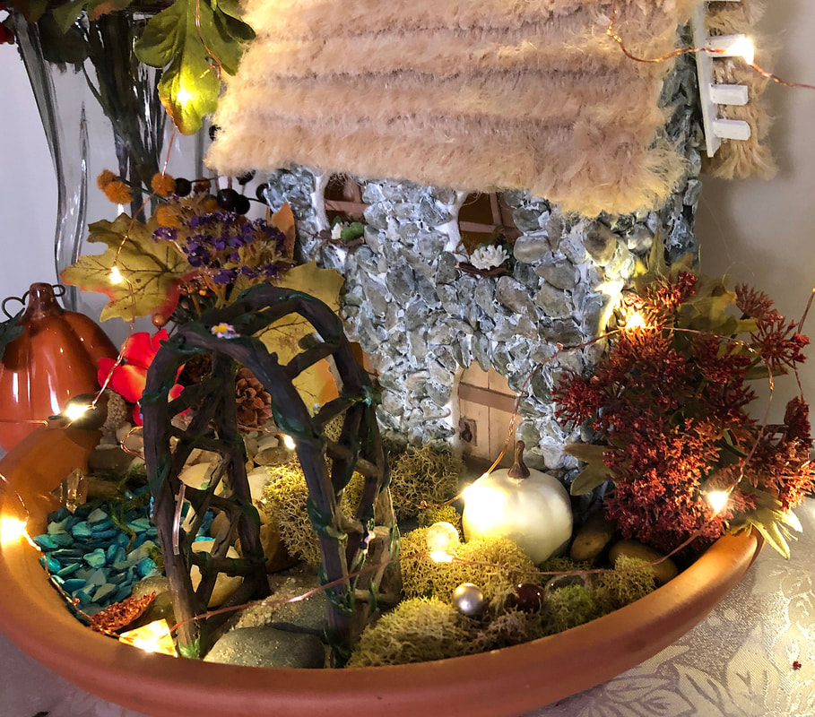 Handcrafted English fairy cottage and fairy garden with Fall faux florals and fairy lights.