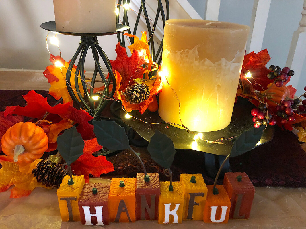 Fall candle vignette with faux florals and thankful sign lit with fairy lights.