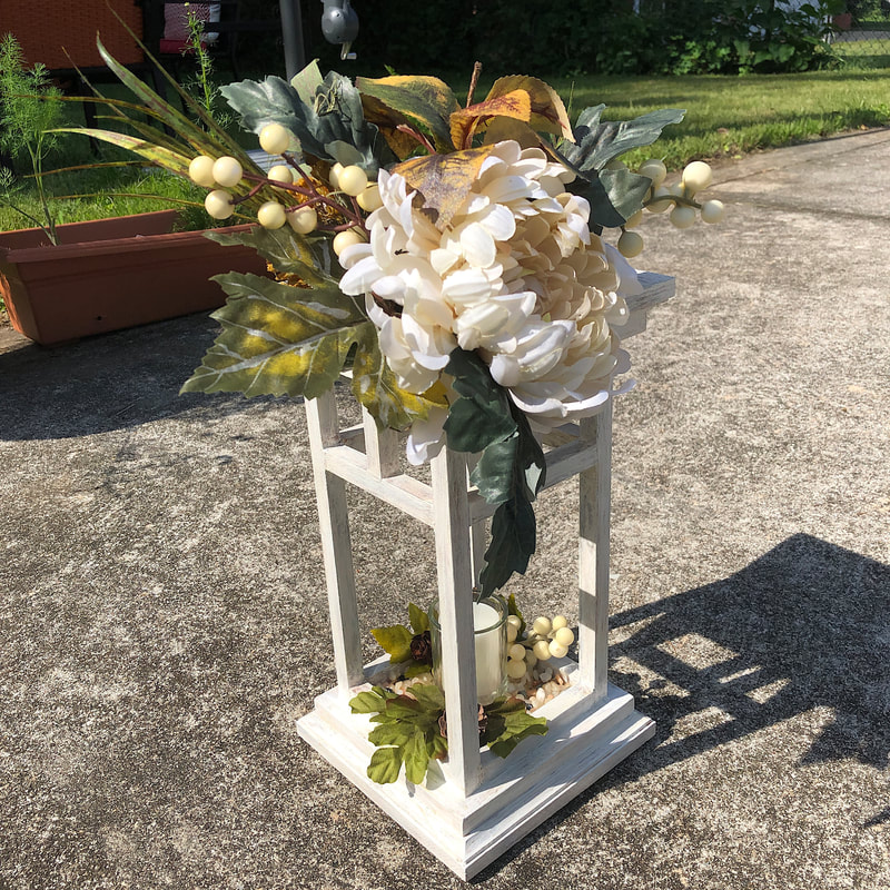 Handcrafted wood lantern with faux florals.