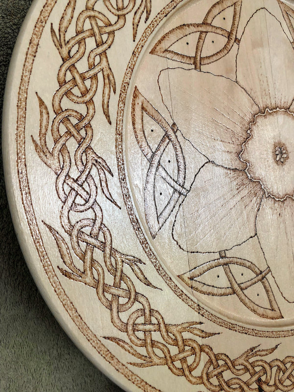 Closeup of artwork details on hand drawn wood burned Celtic inspired decorative plate.