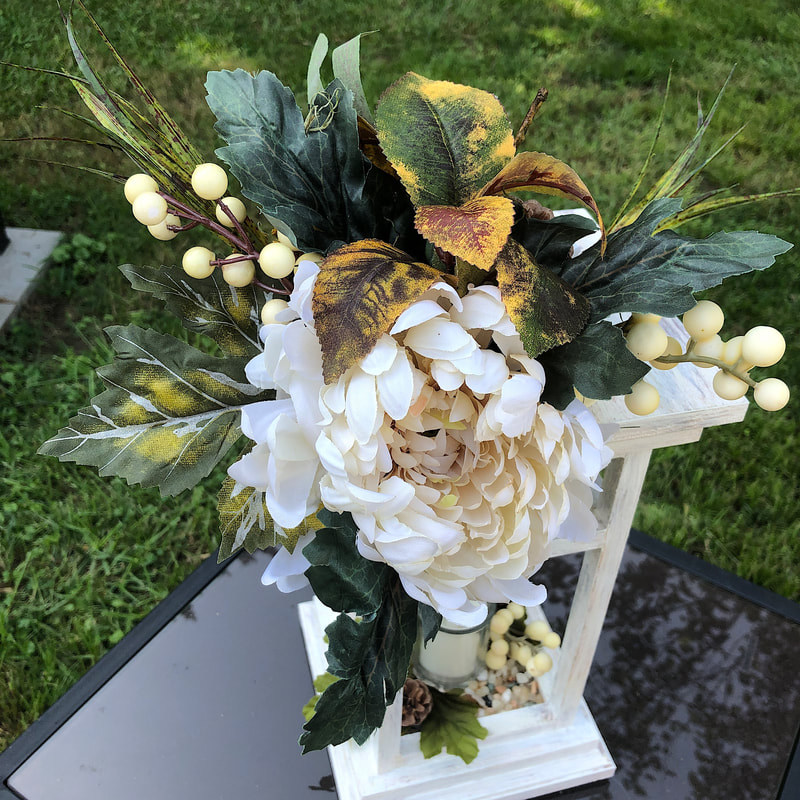 Faux floral arrangement on top of a handcrafted wood lantern.