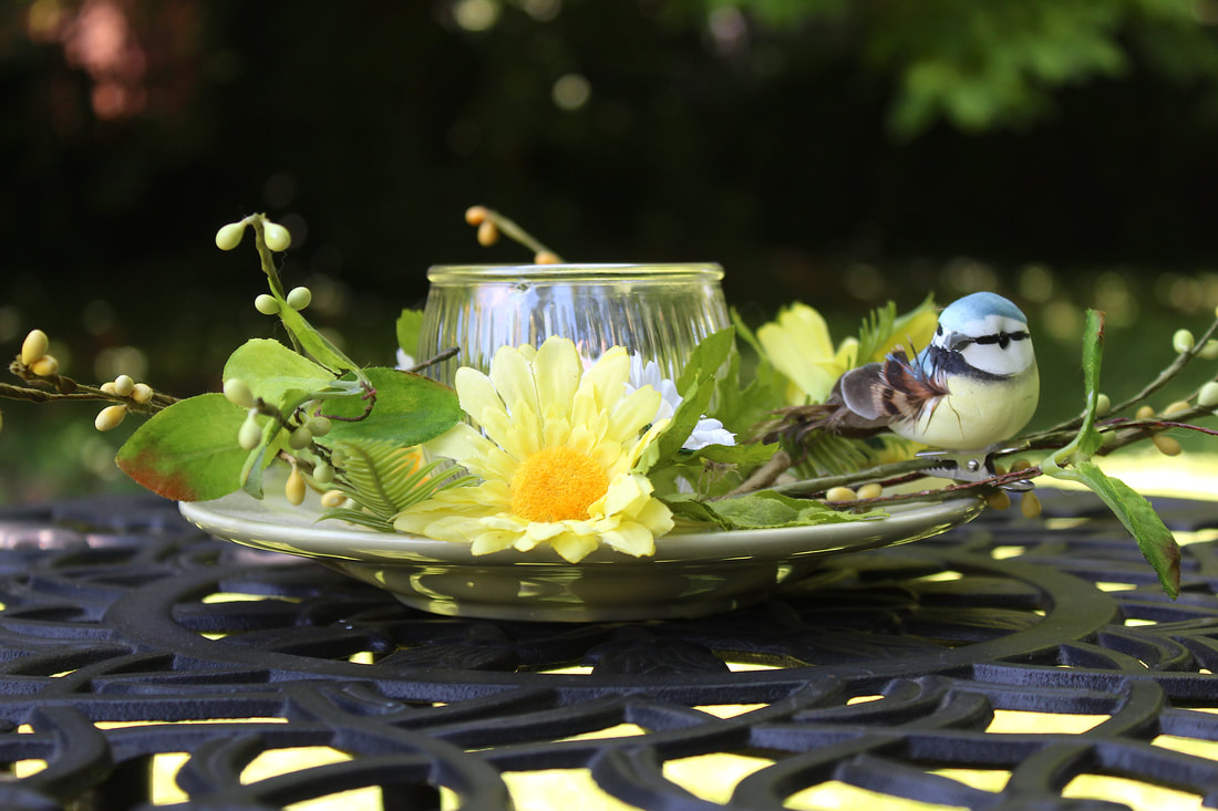 Faux floral candle ring and bird on a repurposed plate with a glass.