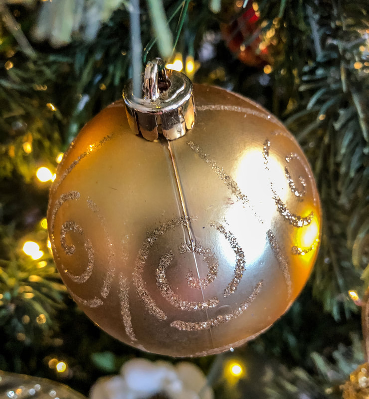 Gold Christmas ornament on a tree.