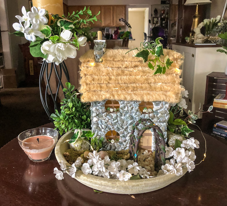 A handcrafted fairy cottage with faux florals.