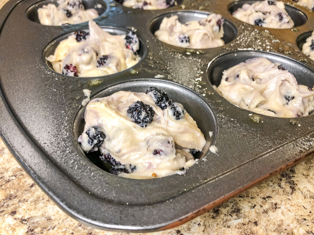 Muffin pan with mulberry muffin batter.