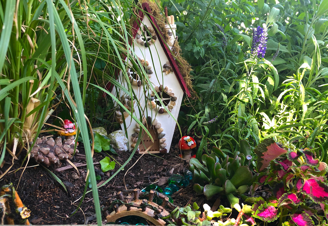 Handcrafted fairy cottage nestled in an outdoor fairy garden