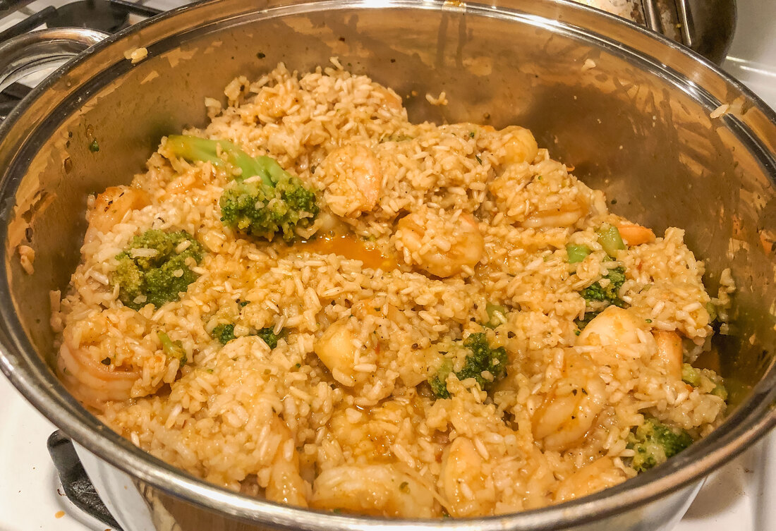 Spicy shrimp and broccoli with rice in a pot.