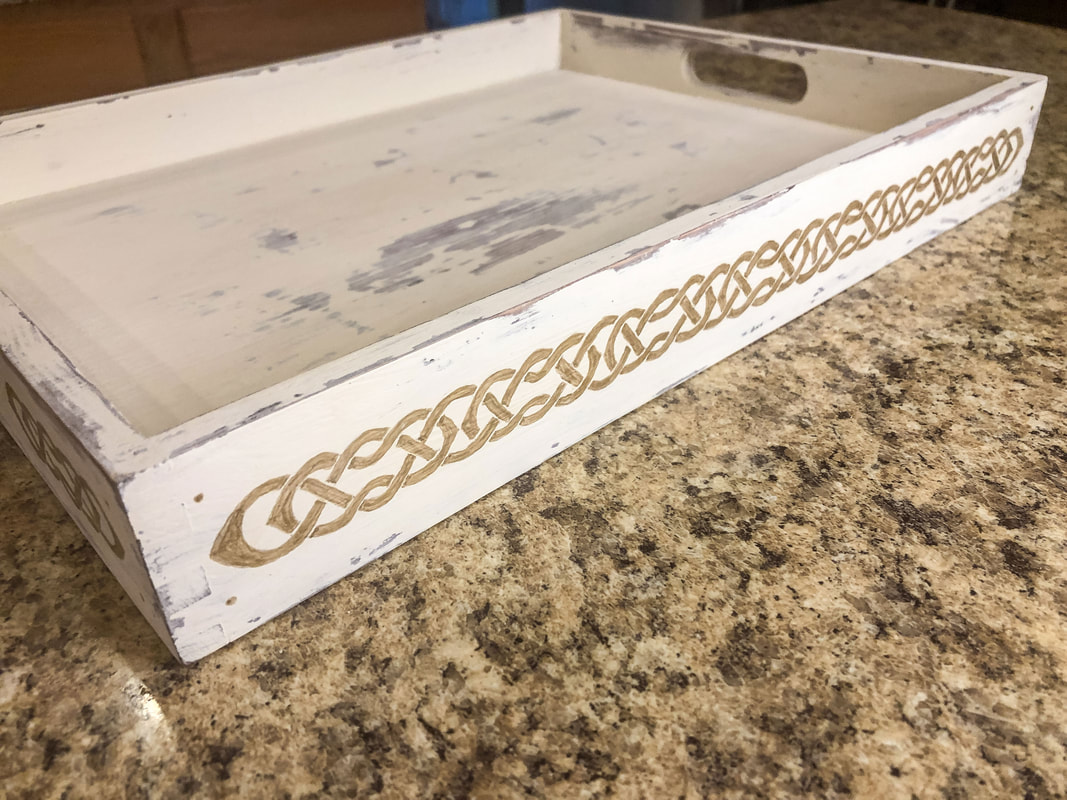 A Celtic knot border painted in gold on the side of a tray.