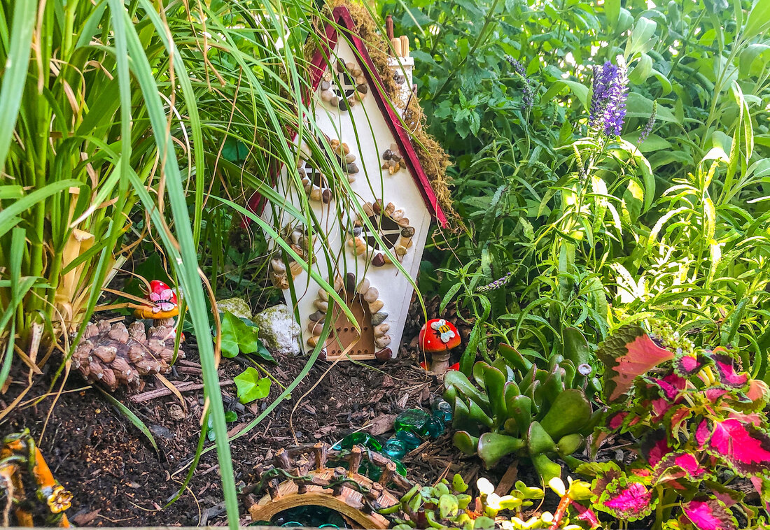 Outdoor fairy garden faeturing a handcrafted miniature fairy cottage.