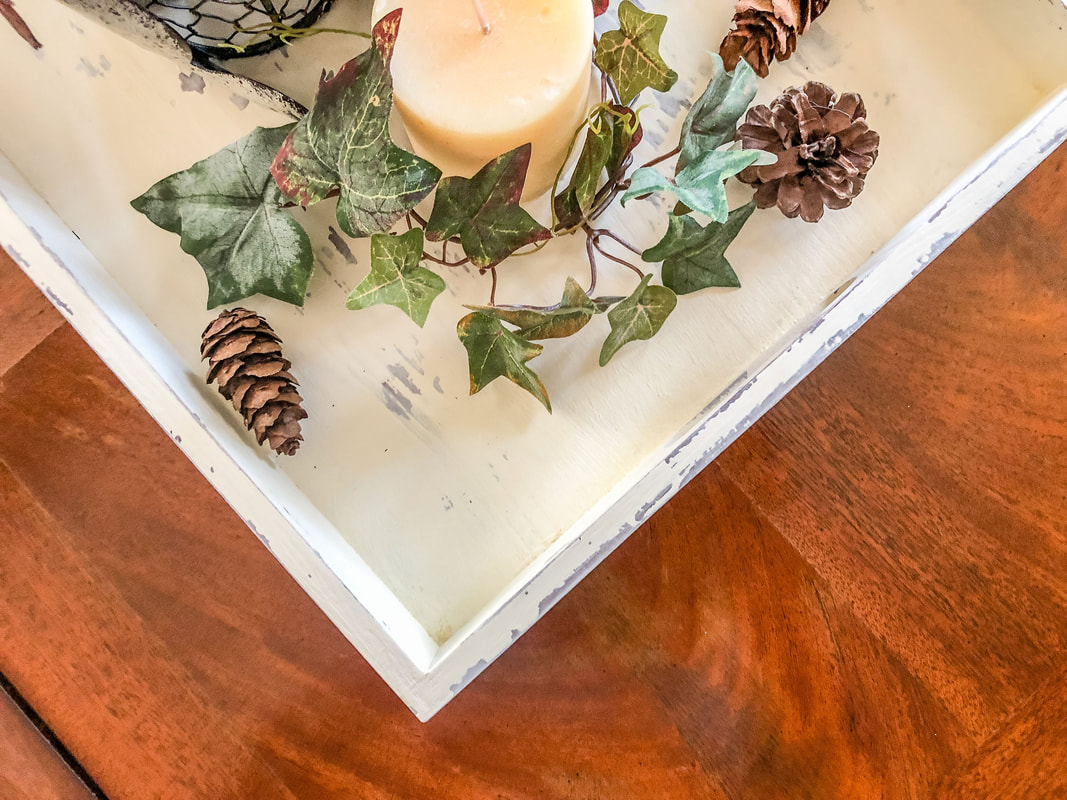 Chalk painted decorative tray with faux ivy and pine cones.