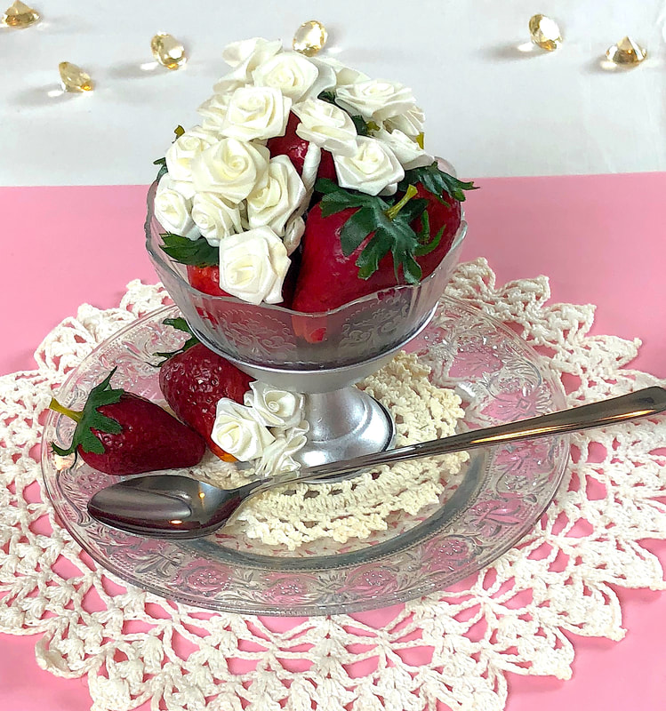 Faux strawberries in a repurposed dessert glass on a glass plate.