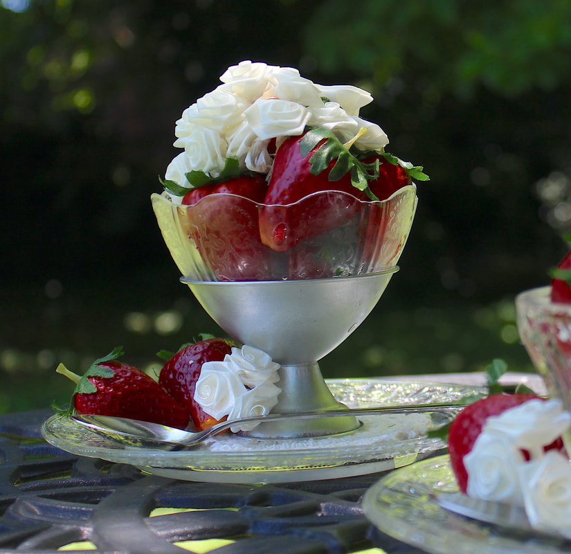 Faux strawberries and mini white faux roses in a repurposed dessert glass.