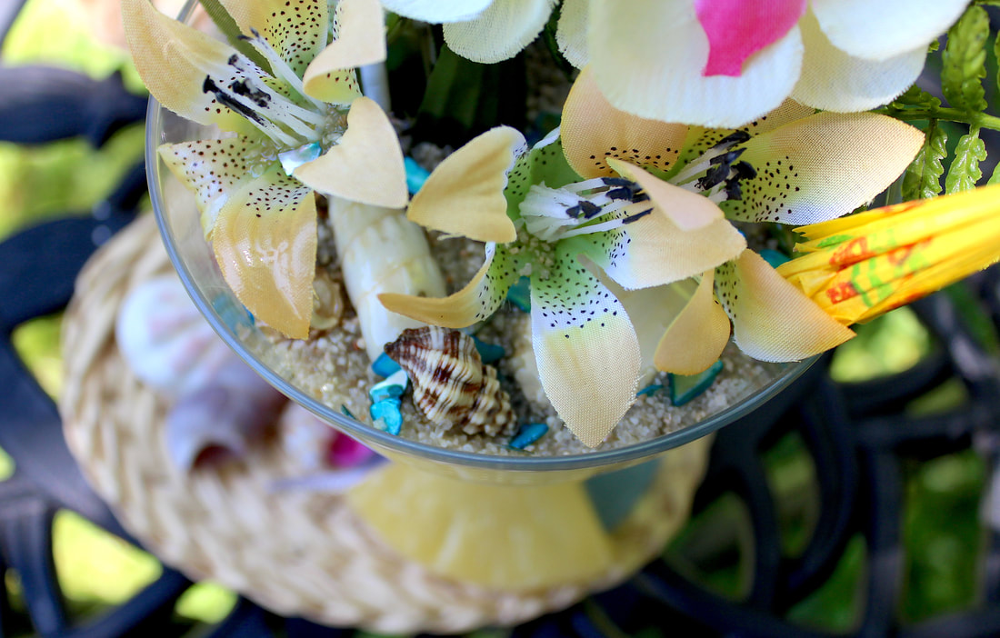 Faux lilies and other tropical decor in a repurposed dessert cup.