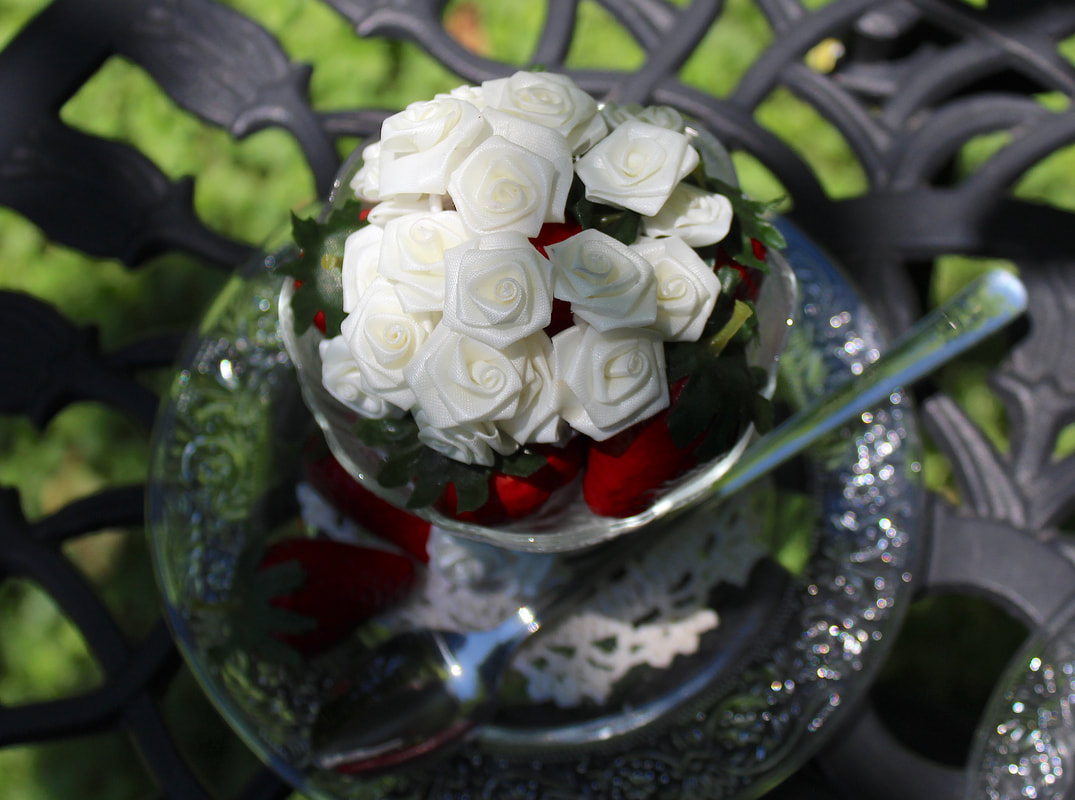 Miniature faux white roses on faux strawberries.
