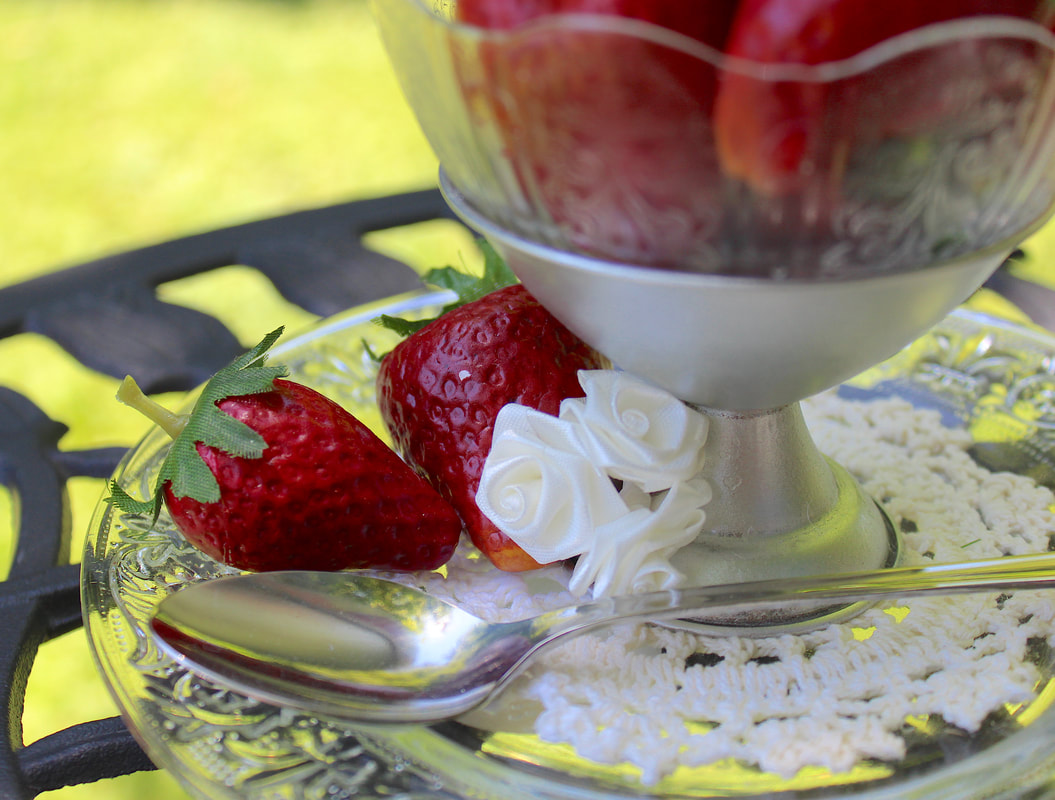 Faux strawberries on a repurposed glass plate with silver spoon.