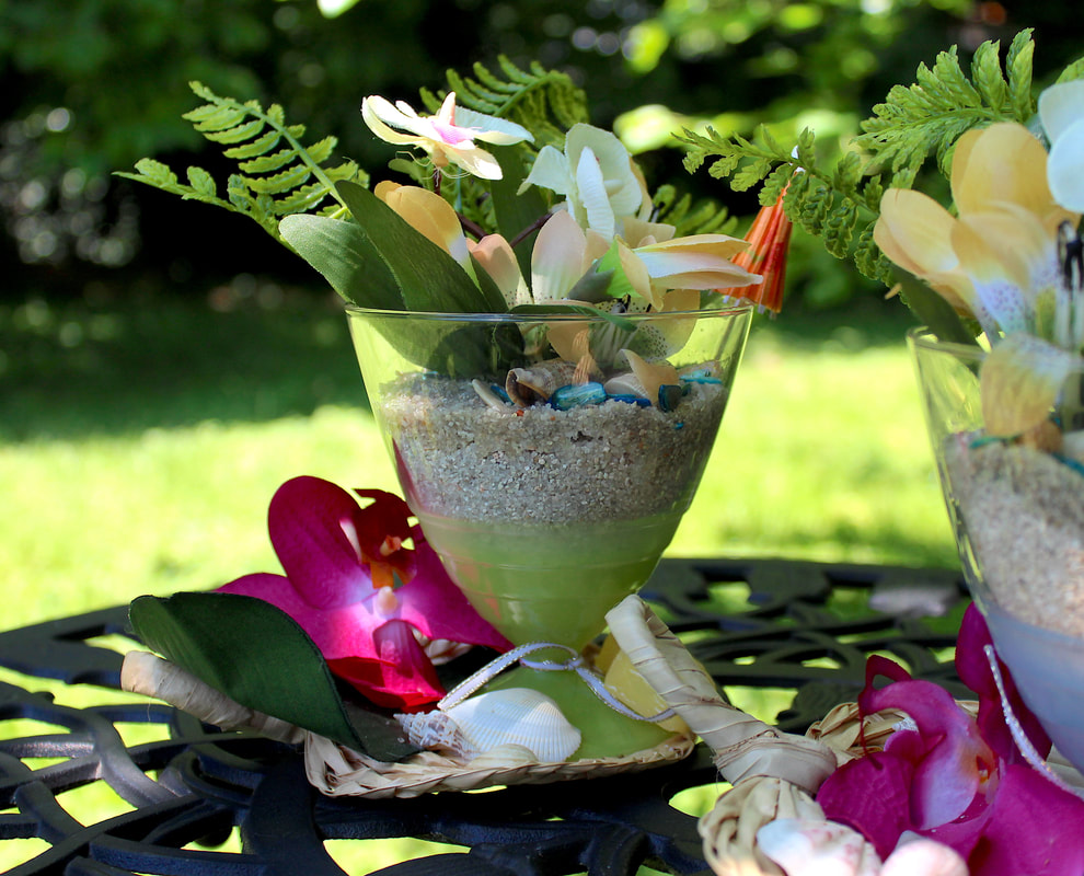 Green dessert glass filled with sand and tropical faux florals