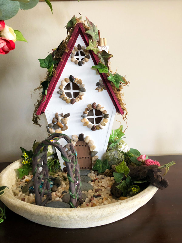 Handcrafted fairy cottage with ivy in an indoor fairy garden.