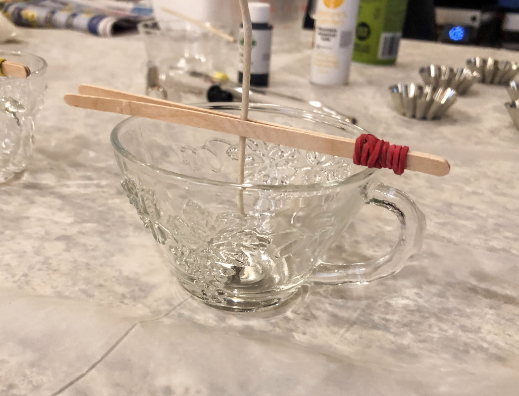 Glass tea cup with wick prepped for homemade candle wax.