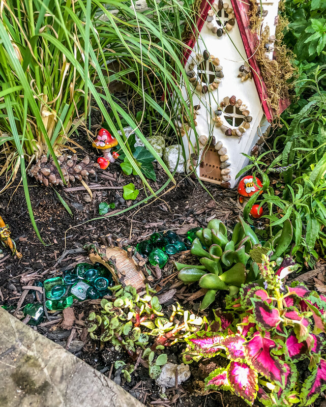 Outdoor fairy garden with a handcrafted fairy house.