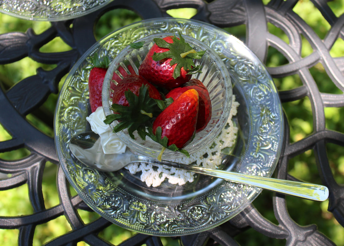 Top down photo of faux strawberries in a glass and on a glass plate.