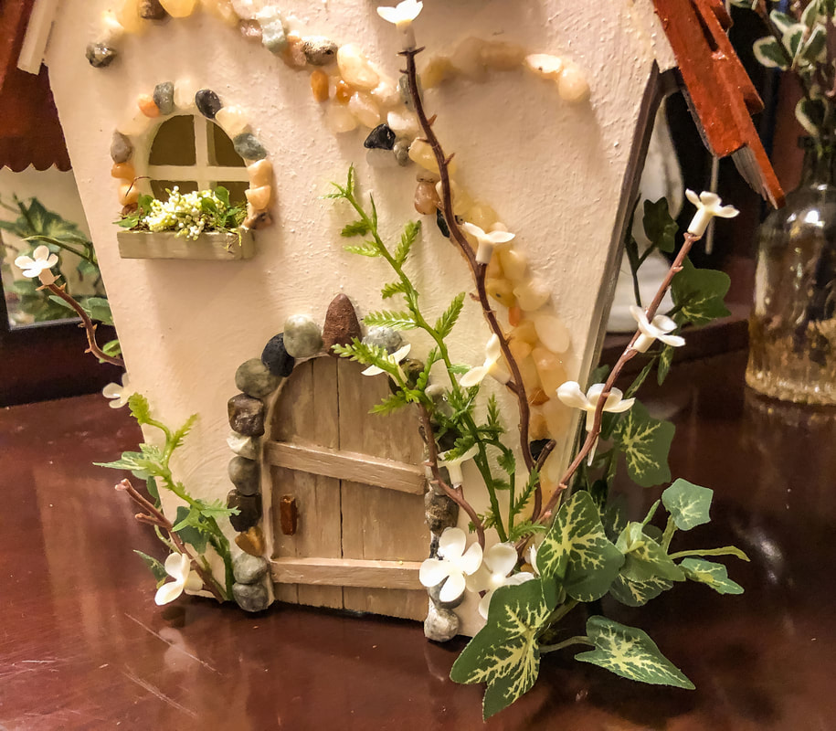 handcrafted fairy house with fairy door and faux florals.