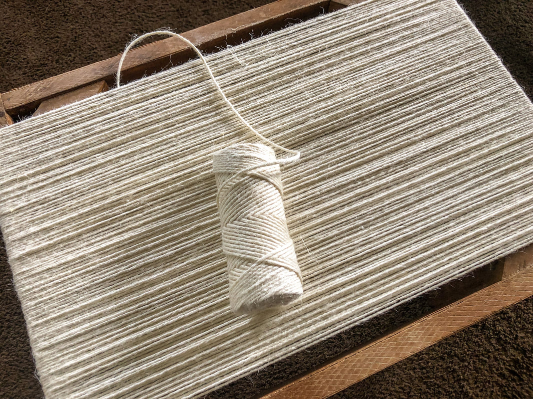Repurposed foot stool being wrapped in jute twine for a DIY project by Di's Studio Designs.