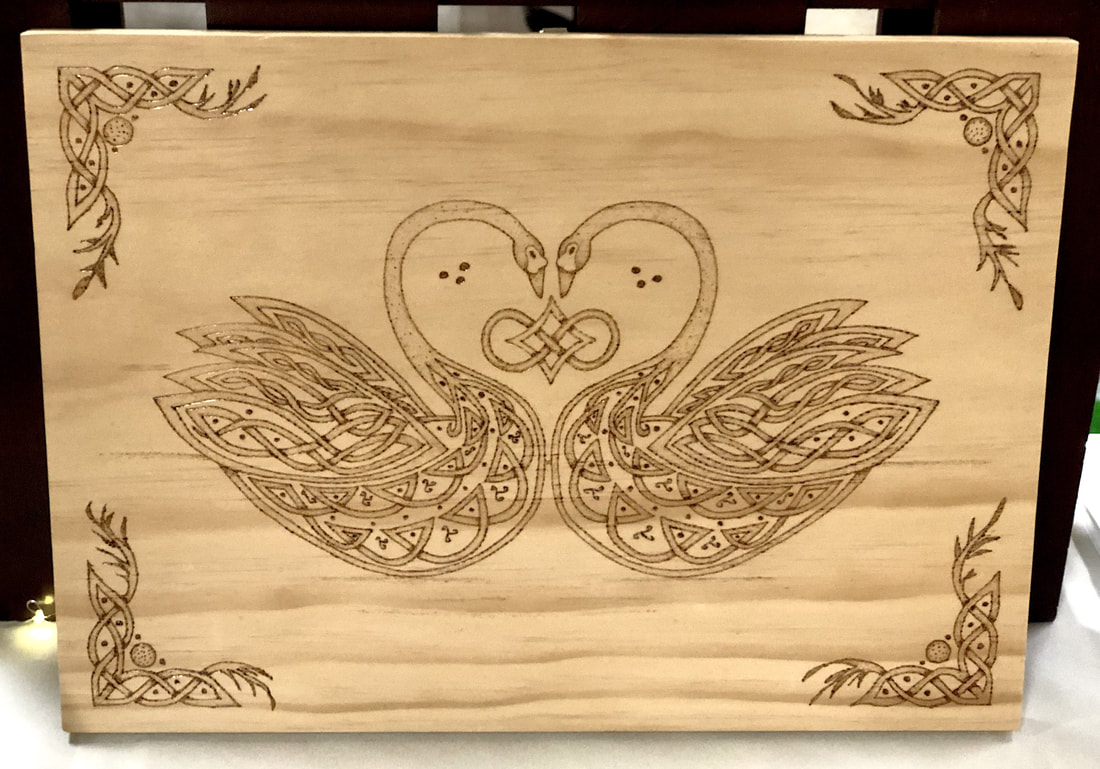 Celtic knotwork style swans wood burned on a plaque.