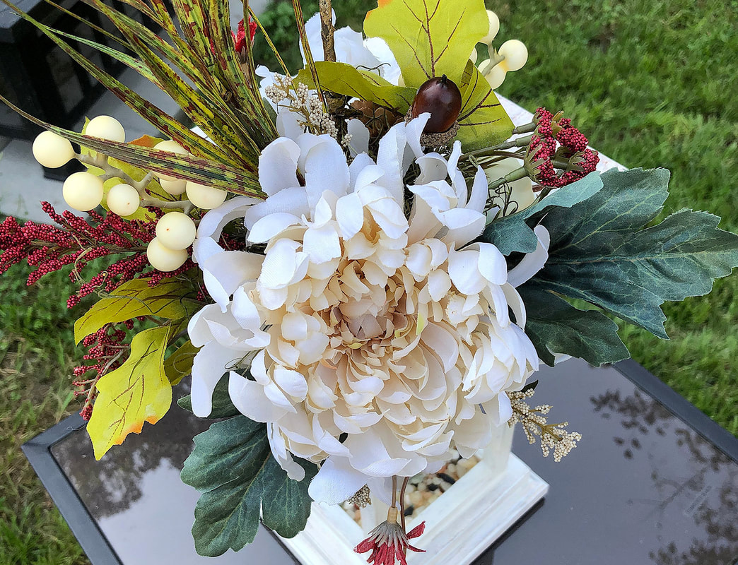 Faux cream flower with red berries and smaller flowers arranged in a bouquet.