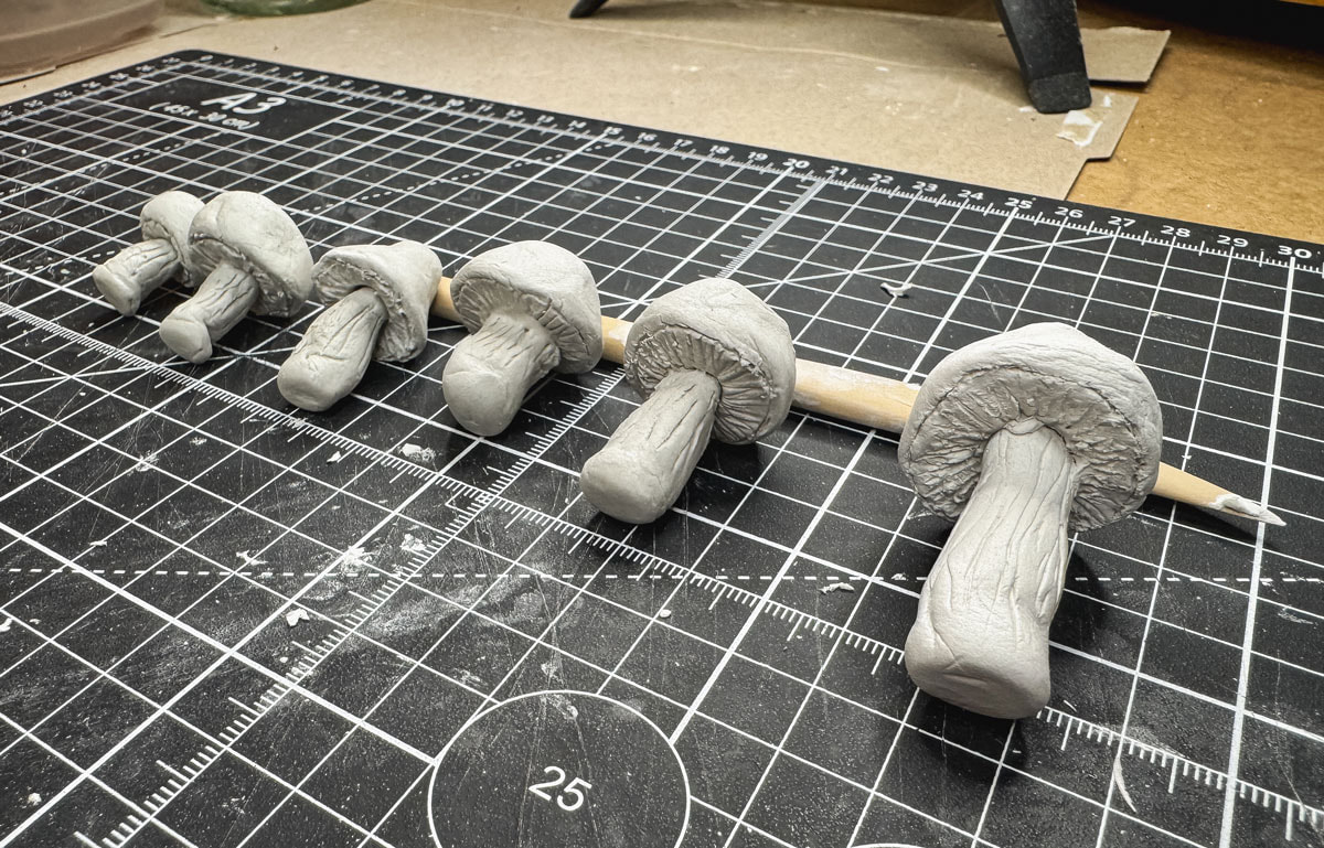 Handmade miniature mushrooms made with air dry clay lined up to dry.