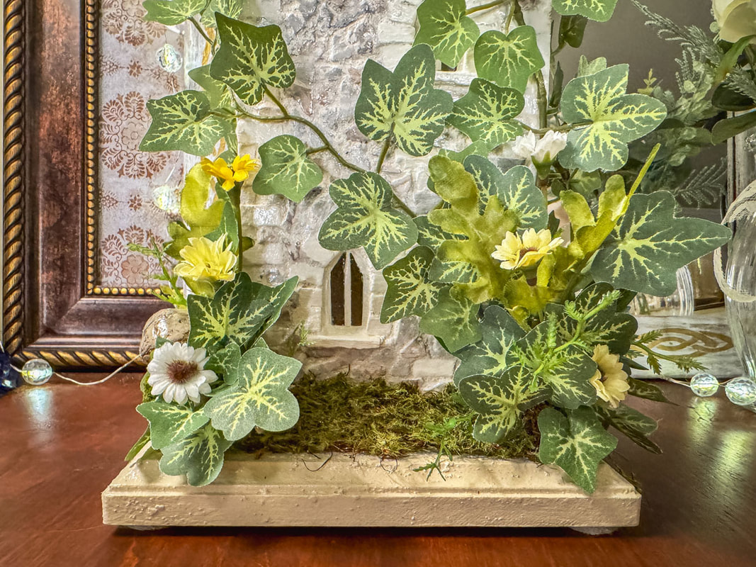Closeup of window and faux florals on a handmade fairy castle.