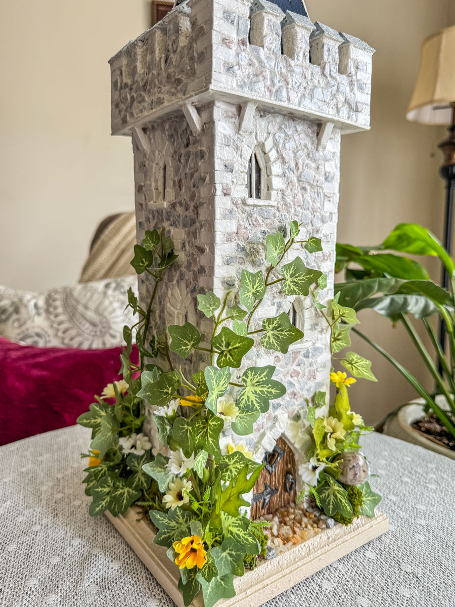 Miniature handcrafted castle tower with faux florals.