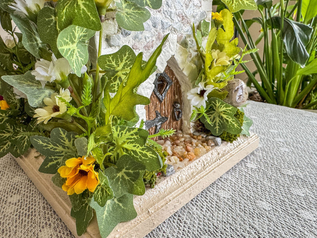 Closeup view of a handmade castle tower entrance and faux florals.